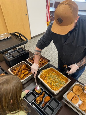 server filling student's lunch tray with food samples