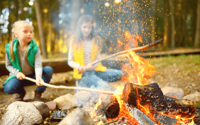 Two young girls tending a campfire