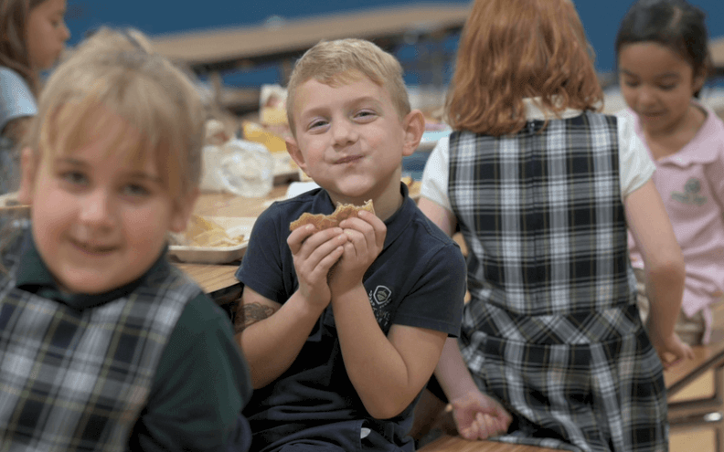 Great Oaks Academy student eating hamburger and smiling